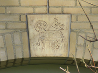 840585 Afbeelding van een sluitsteen met het oud-christelijk symbool van het Lam Gods, boven een boogvormige ingang aan ...